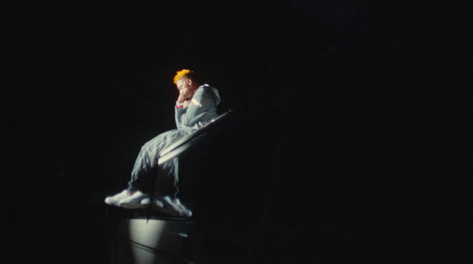 a man in a white suit standing on a black surface