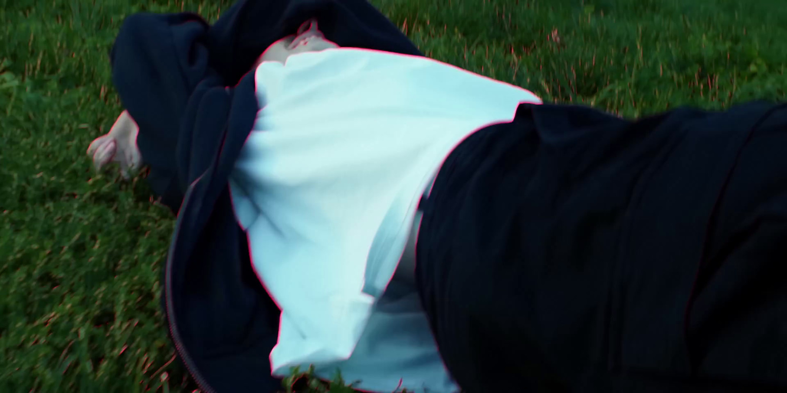 a person laying in the grass with a bag on their back