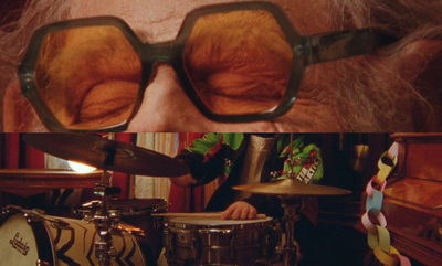 a close up of a person wearing glasses near a drum set