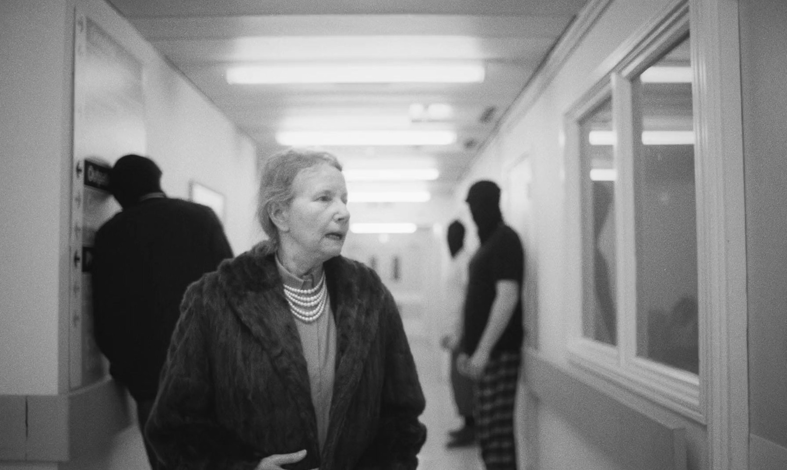 a black and white photo of a woman walking down a hallway