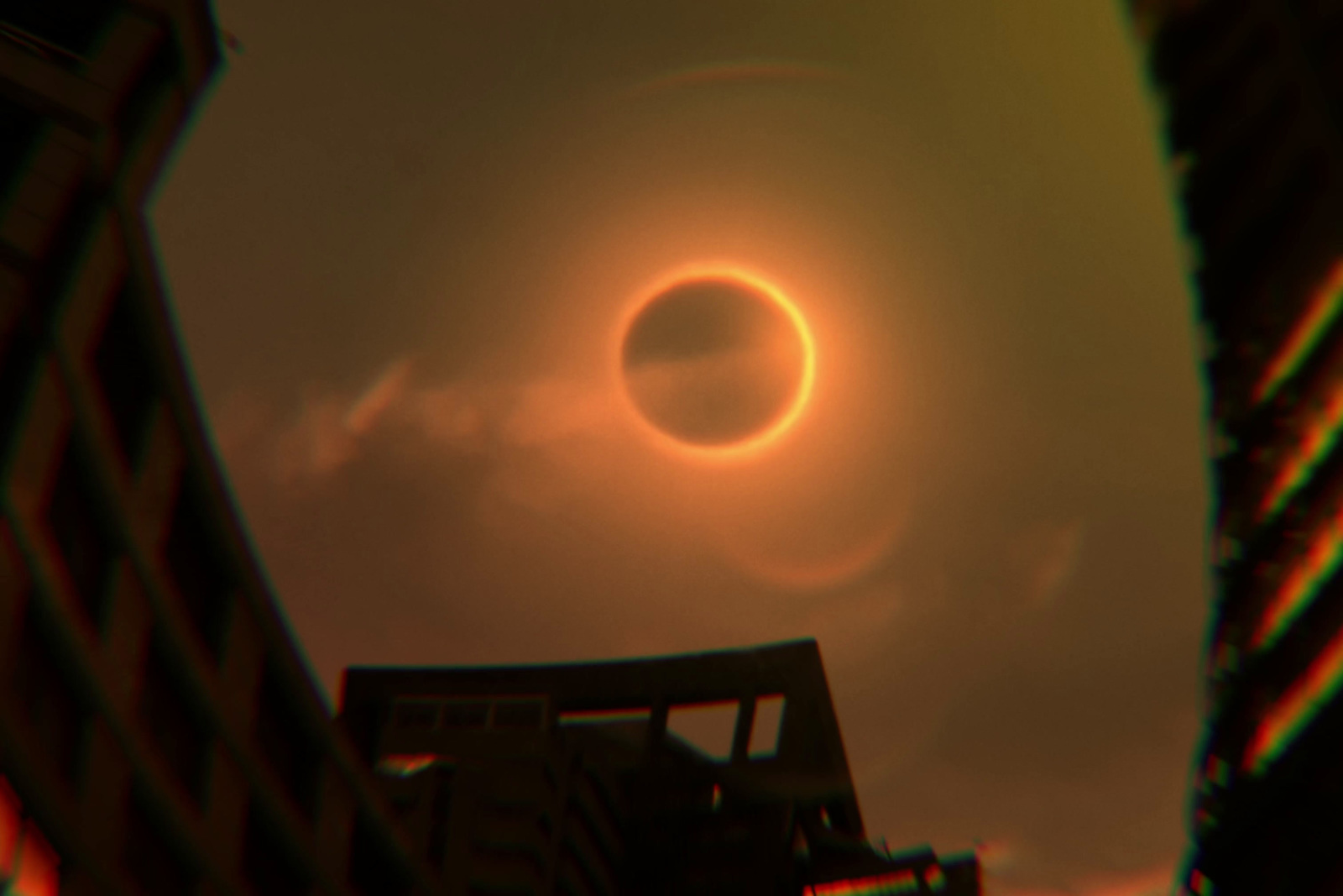 a solar eclipse seen through a pair of buildings