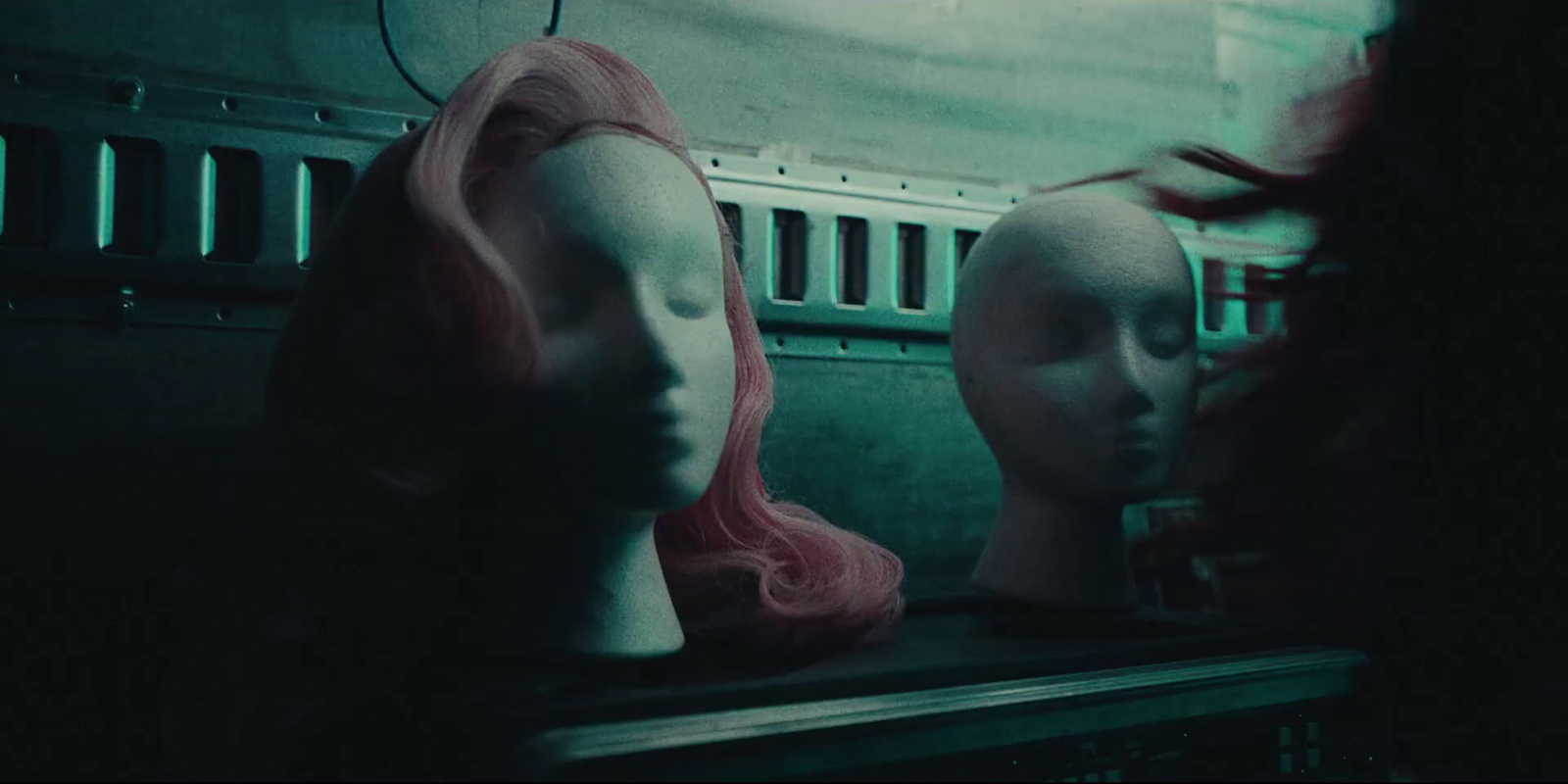 two mannequins with pink hair in a dark room