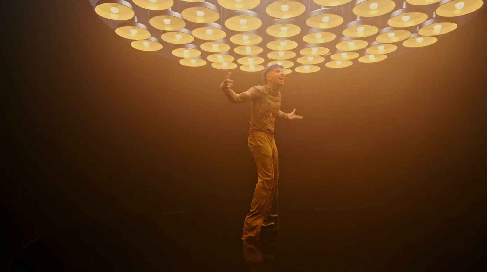 a man standing on top of a stage under a light fixture