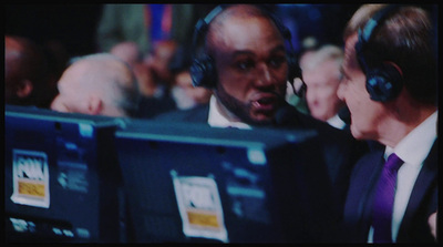 a man in a suit and headphones talking to another man in a suit