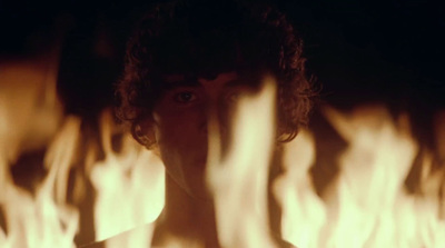 a man in a dark room with fire in the background