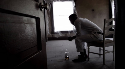 a man sitting in a chair next to a bottle of alcohol