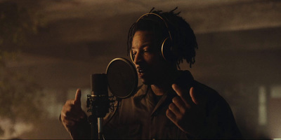 a man with dreadlocks standing in front of a microphone