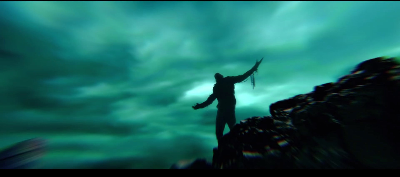 a man standing on top of a mountain under a cloudy sky