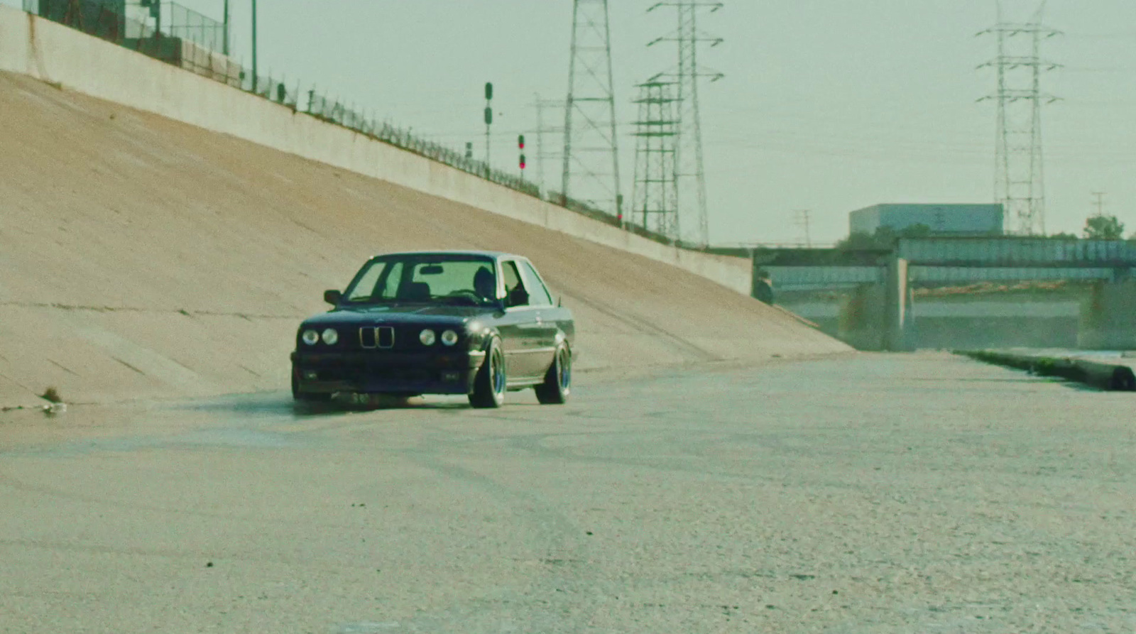 a black car driving down a road next to a hill