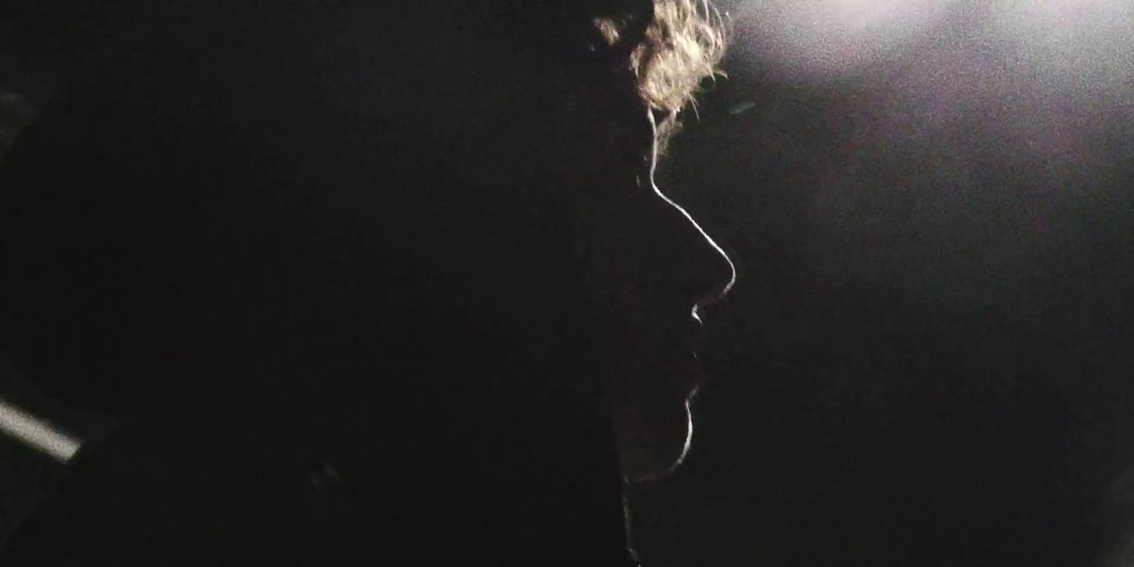 a man standing in front of a microphone in a dark room