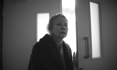 a black and white photo of a woman standing in front of a door