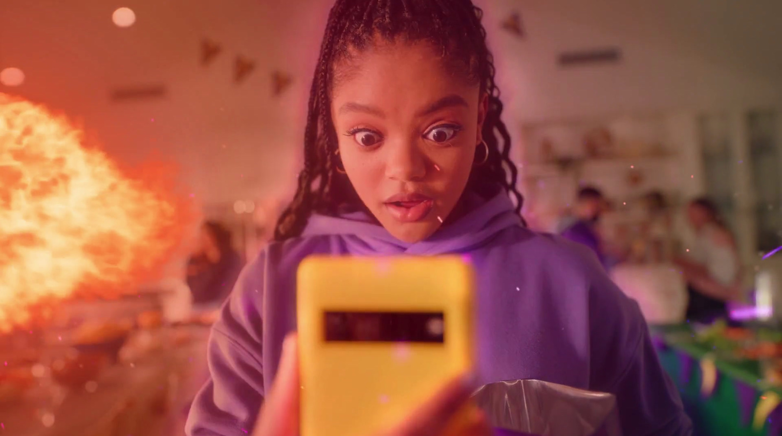 a young girl holding a cell phone in front of a fire