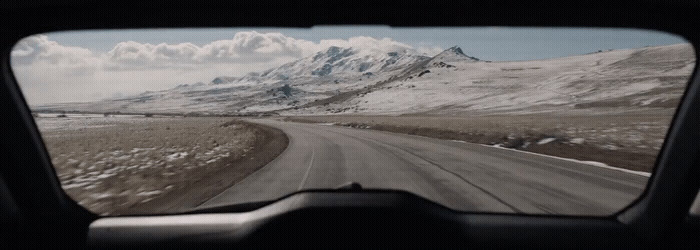 a view of a snowy mountain range from a vehicle's windshield