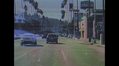 a car driving down a street next to tall palm trees