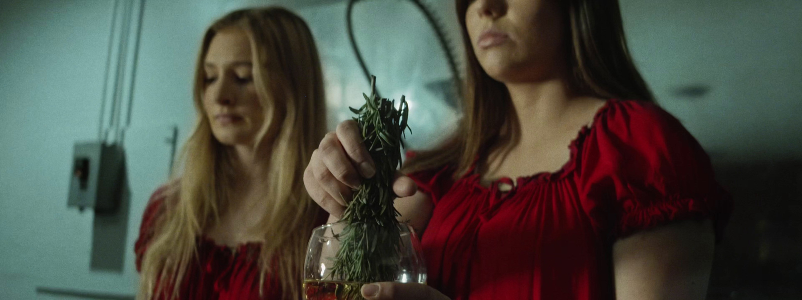 two women in red dresses holding a glass of wine