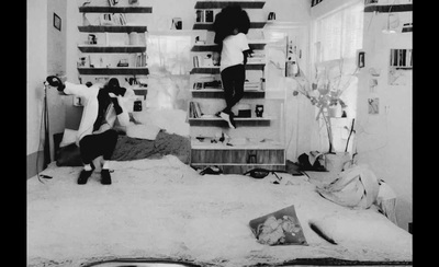 a black and white photo of a person jumping on a bed