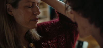 a woman putting a necklace on another woman's neck