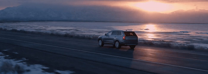 a car driving down a road next to the ocean