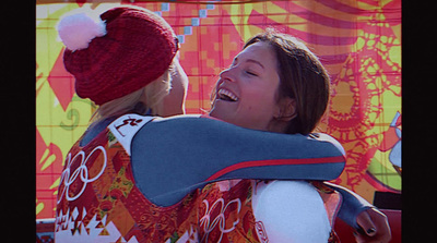 a woman is hugging another woman in front of a colorful wall