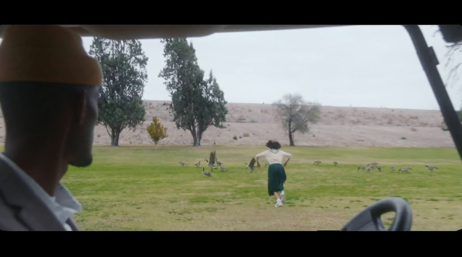 a man standing in a field next to a car