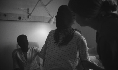 a group of people standing around a bed in a room