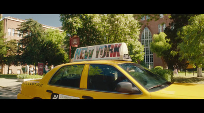 a yellow taxi cab driving down a street next to a tall building