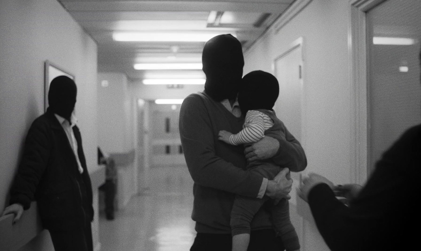 a person in a mask holding a child in a hallway