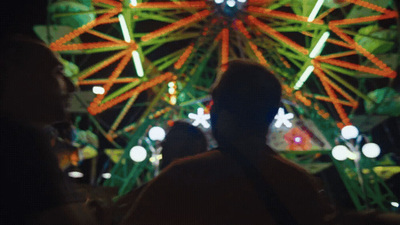 a person standing in front of a ferris wheel at night