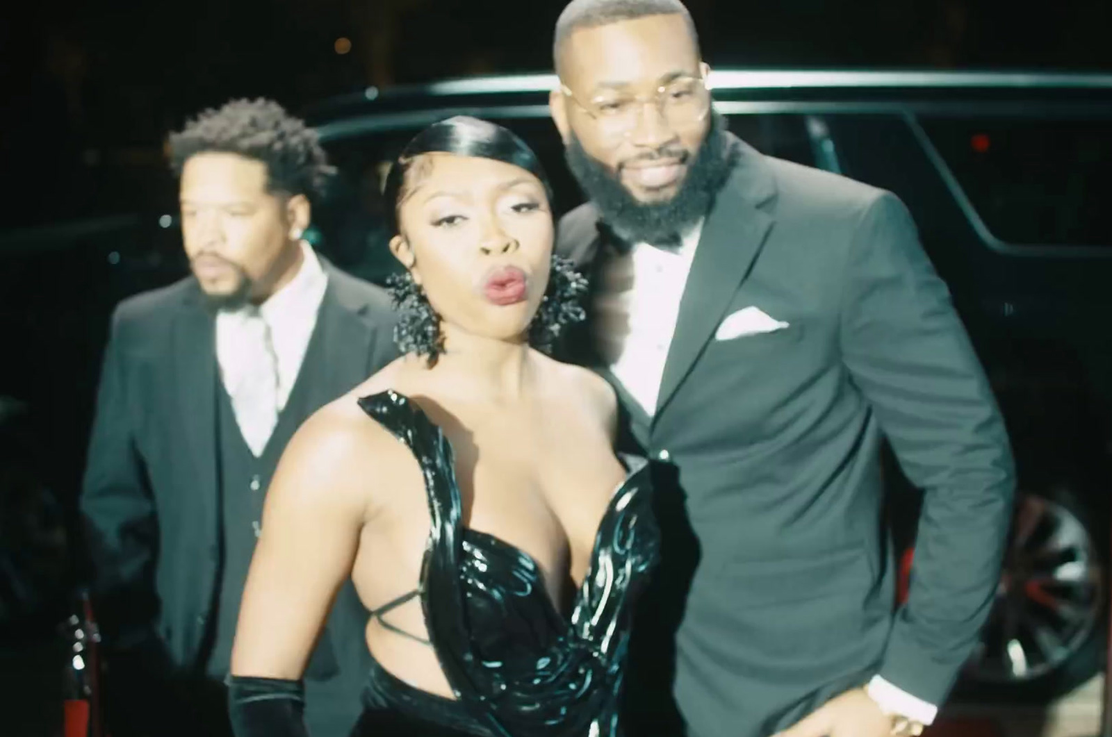 a man and a woman standing next to each other in front of a car