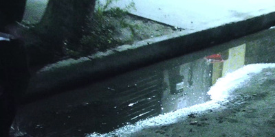 a puddle of water with a red umbrella in it