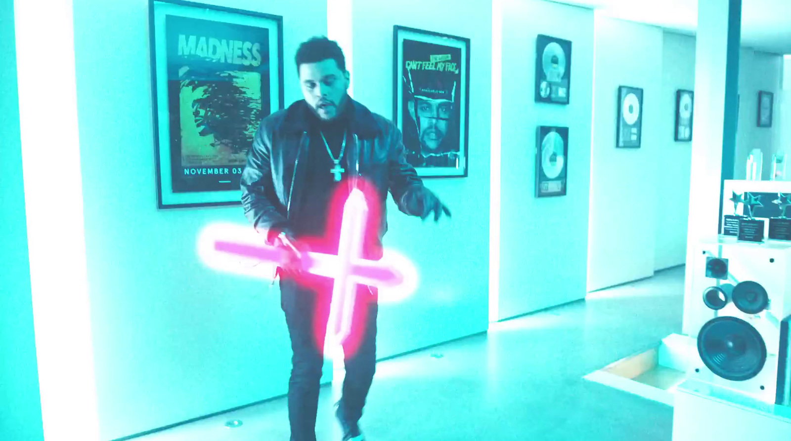 a man is holding a neon cross in a hallway