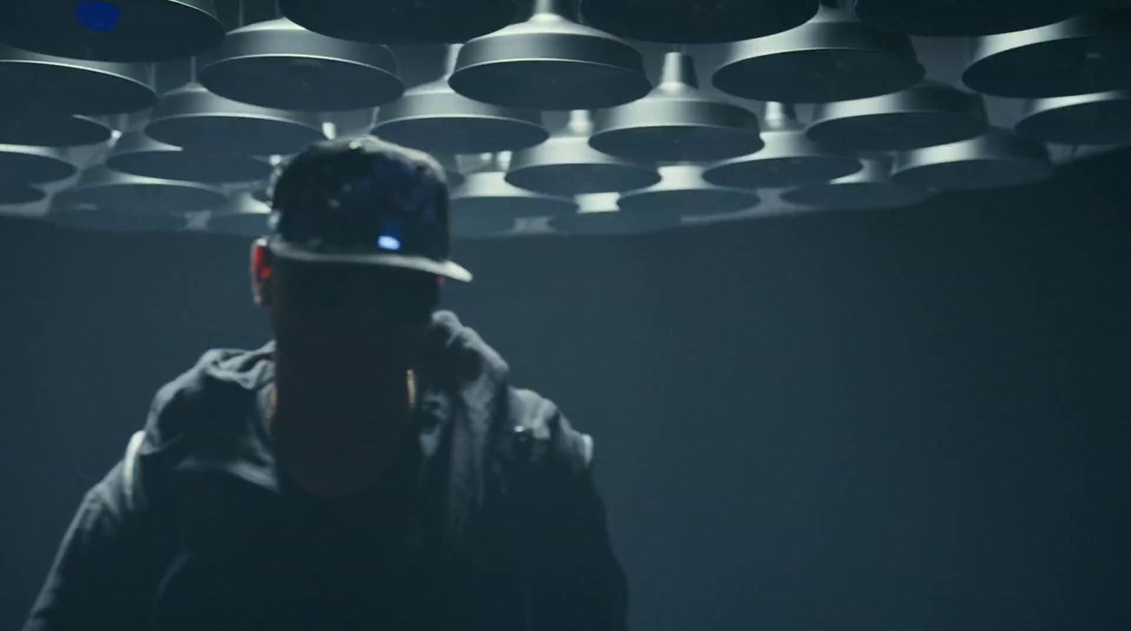 a man wearing a hat standing in a dark room