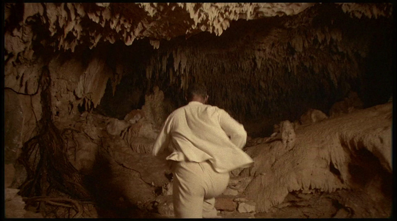 a man in a white suit is standing in a cave