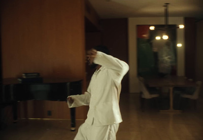 a man in a white suit standing in front of a piano