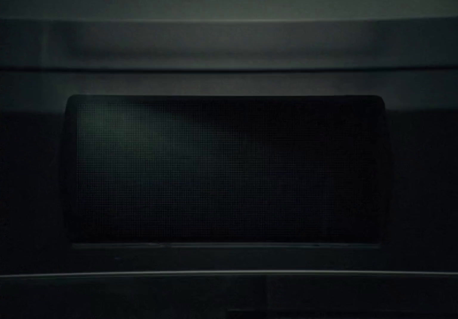 a microwave oven with a light on in a dark room