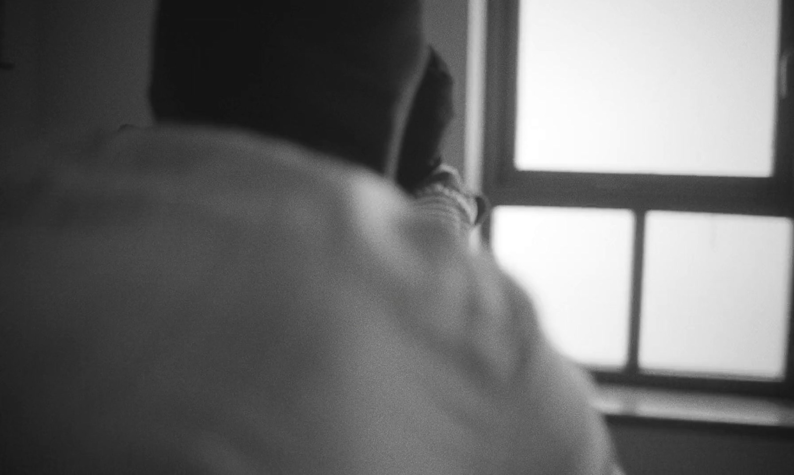 a black and white photo of a person looking out a window