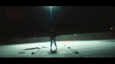 a person standing in the middle of a parking lot at night