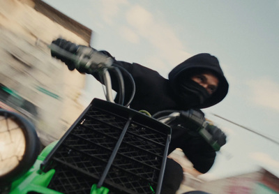 a man in a black hoodie riding a green motorcycle