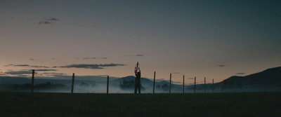 a field with a fence and mountains in the background