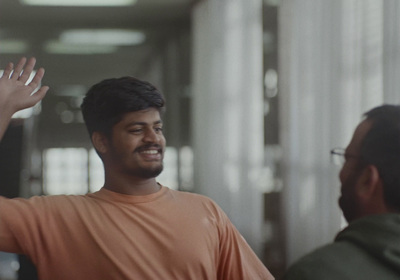 a man in an orange shirt waves to another man