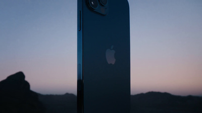 a close up of a cell phone with a mountain in the background