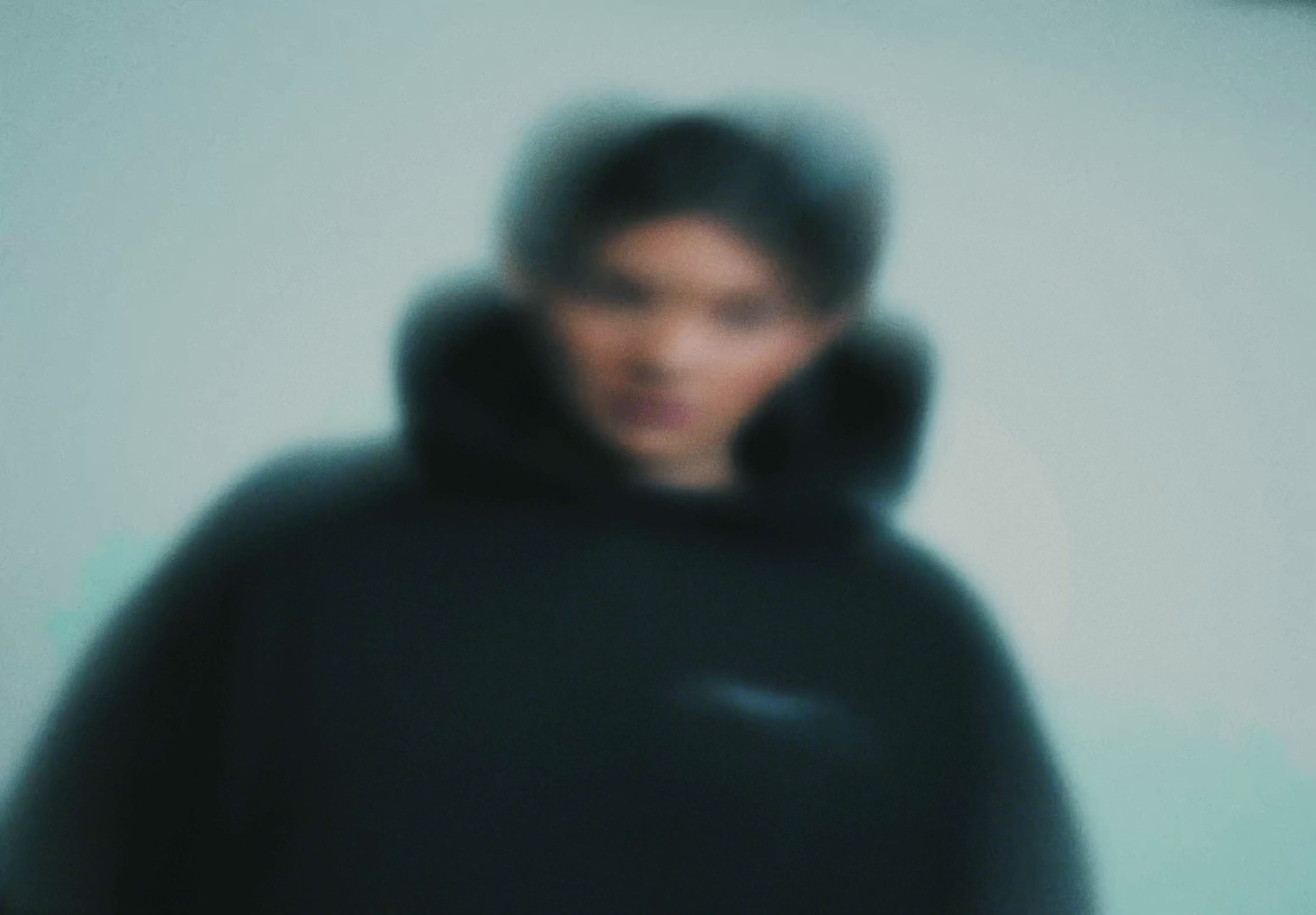 a blurry photo of a man in a black hoodie