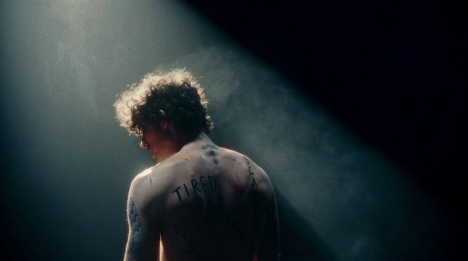 a man with a tattoo on his back standing in a spotlight