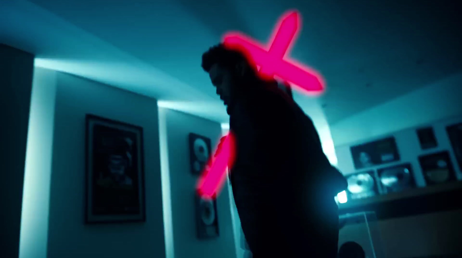 a man standing in a room with a neon cross on his forehead