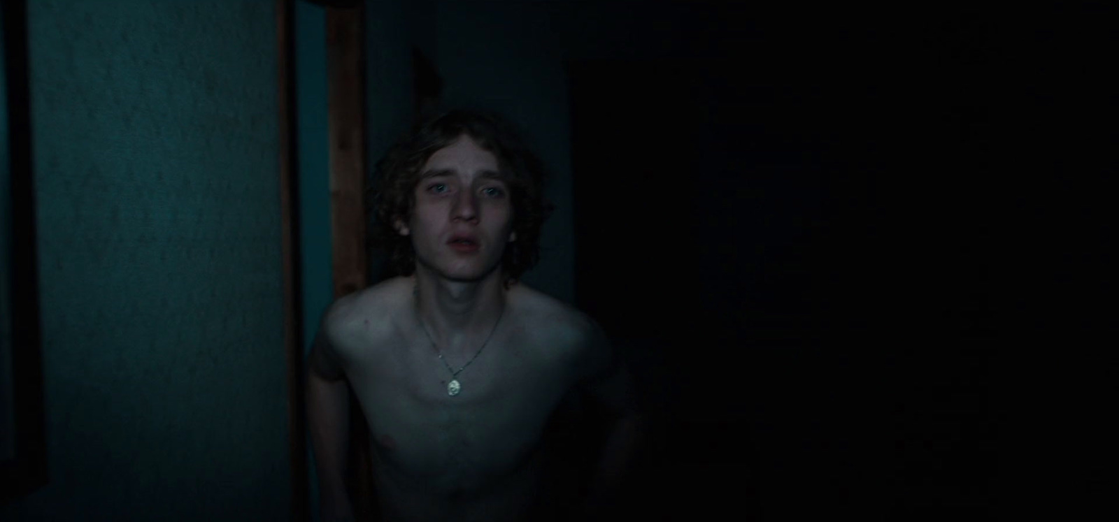 a shirtless man standing in a dark room