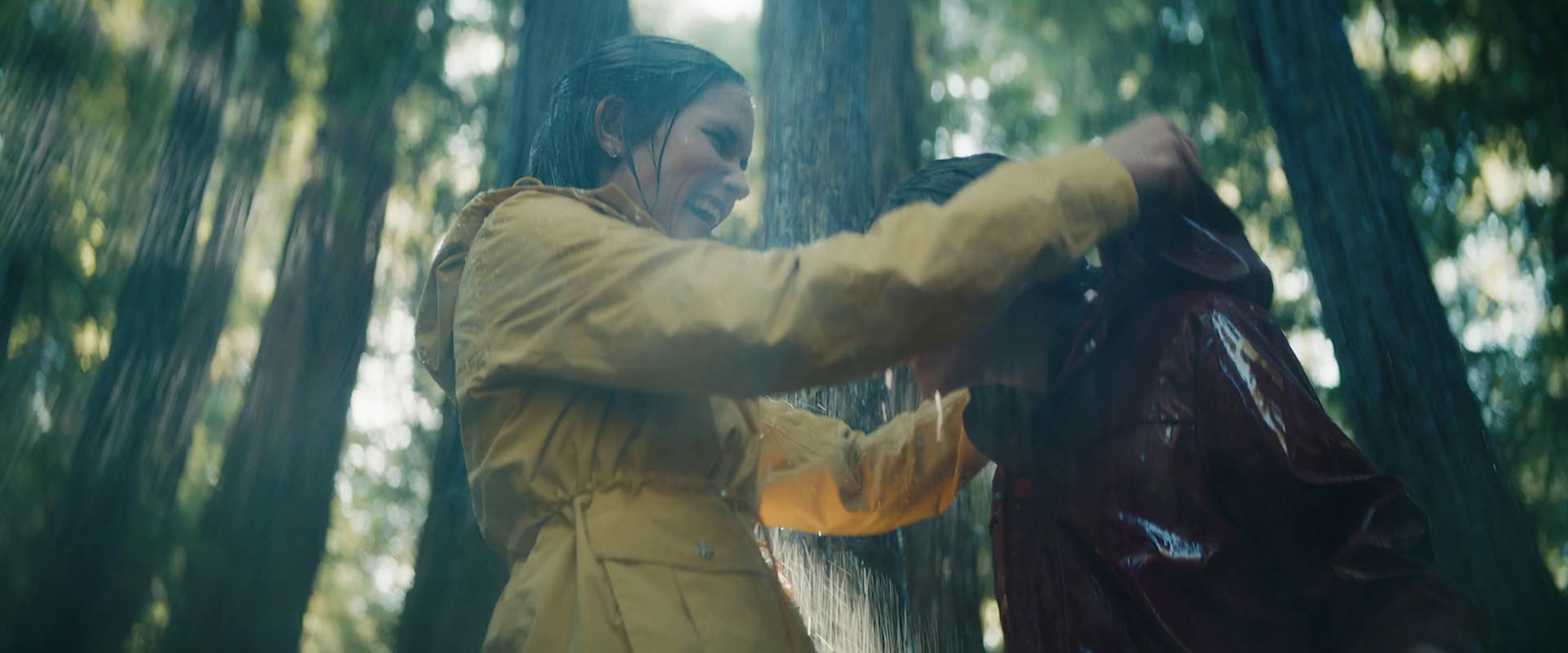 a woman in a yellow raincoat is standing in the woods