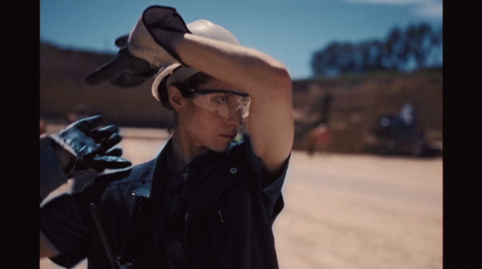 a man with a hat and glasses holding his hat over his head