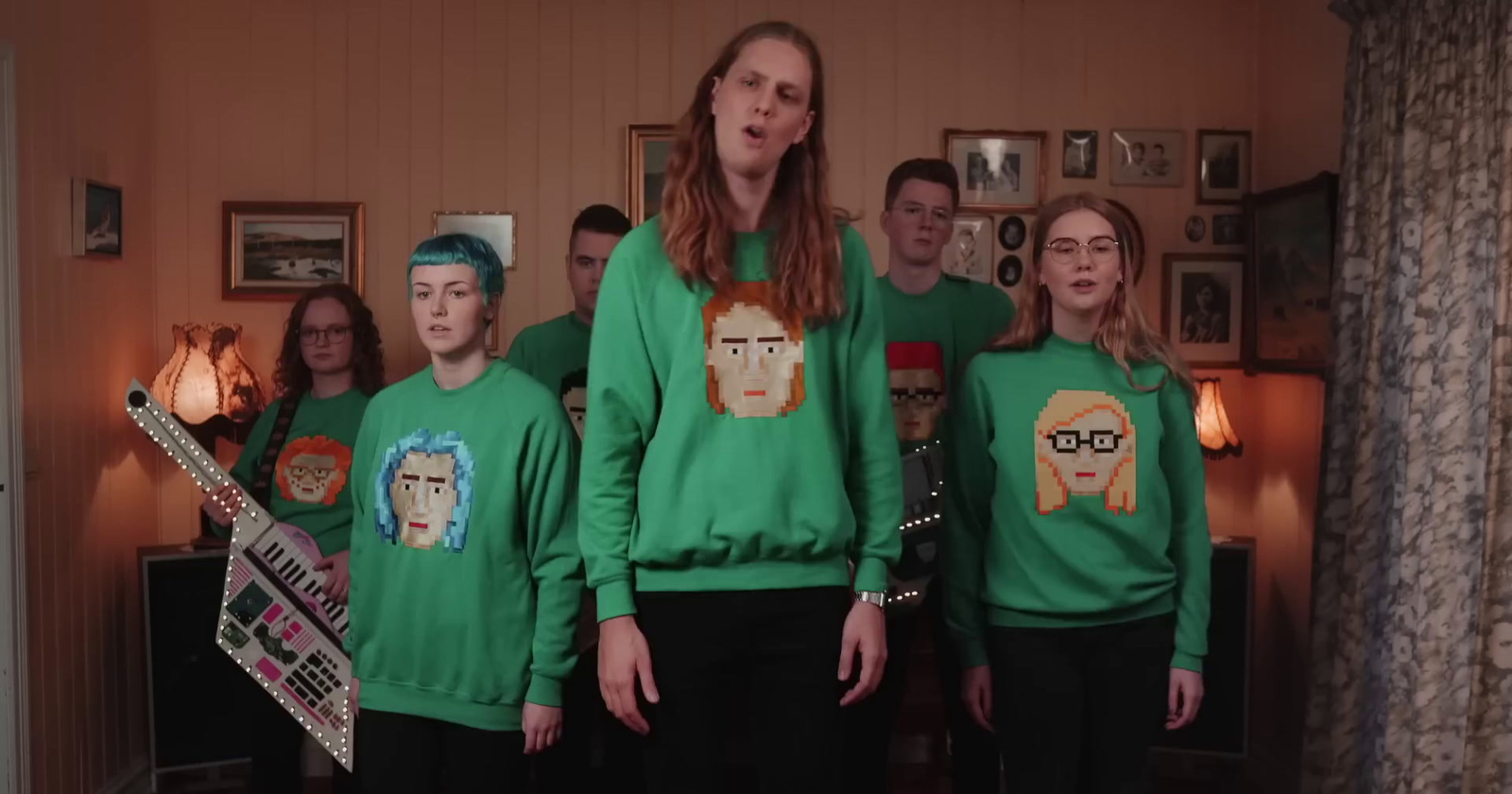 a group of people wearing green sweaters standing next to each other