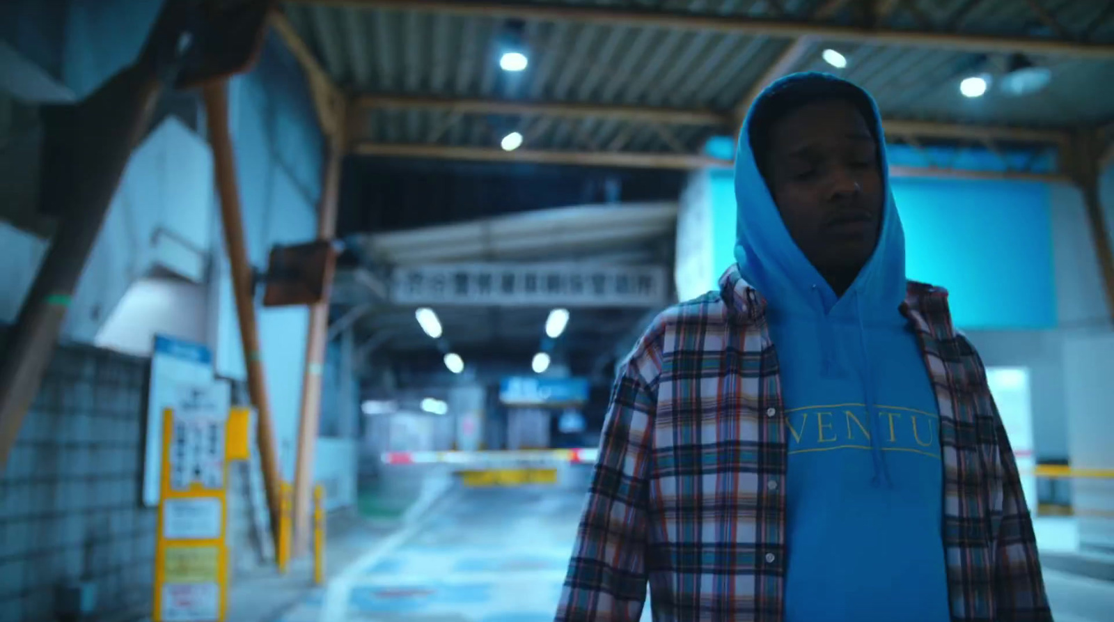 a man wearing a blue hoodie standing in a warehouse