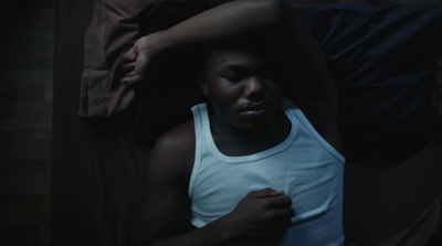 a man in a tank top laying on a bed